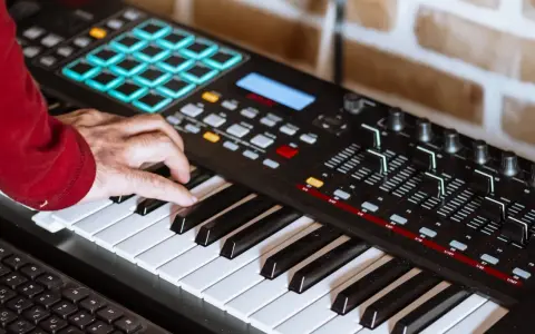 Hand spielt auf einem Keyboard, das für die Erzeugung von Synth-Musik verwendet wird. Viele Knöpfe und Pads sind sichtbar.
