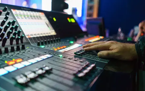 Hand bedient Mischpult für professionelles music management. Lichter und Regler zeigen die komplexe Steuerung.