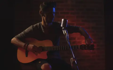 Mann stimmt seine Gitarre, bereit für die Aufnahme. Die Gitarren-Tunings sind entscheidend für den perfekten Klang.