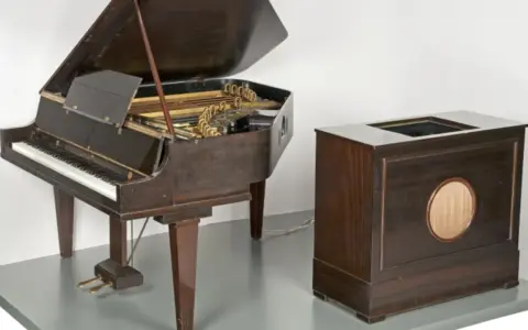 Ein Flügel und ein Holzgehäuse mit Lautsprecher, die zusammen den Beginn des Electronica-Genres markieren.