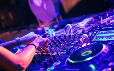 Hände am DJ-Pult, die die Regler für verschiedene techno genres bedienen. Neonlicht und pulsierende Beats.