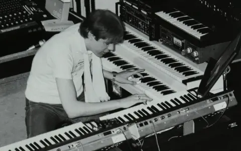 Mann spielt auf mehreren Synthesizern, die typische Klänge der 80er Jahre erzeugen.