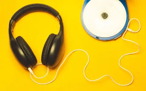 Kopfhörer und ein Discman auf gelbem Hintergrund. Perfekt, um neue Musik zu promoten und den Sound zu genießen.
