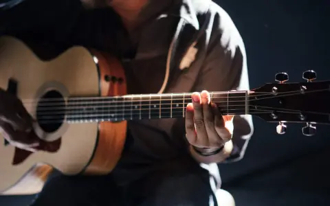 Gitarrist übt den **palm mute**-Effekt auf einer Akustikgitarre, die Finger liegen auf den Saiten.
