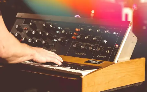 Hand spielt auf einem legendären Minimoog-Synthesizer, der den unverwechselbaren Sound der 70er Jahre prägte.