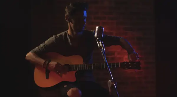 Mann stimmt seine Gitarre, bereit für die Aufnahme. Die Gitarren-Tunings sind entscheidend für den perfekten Klang.