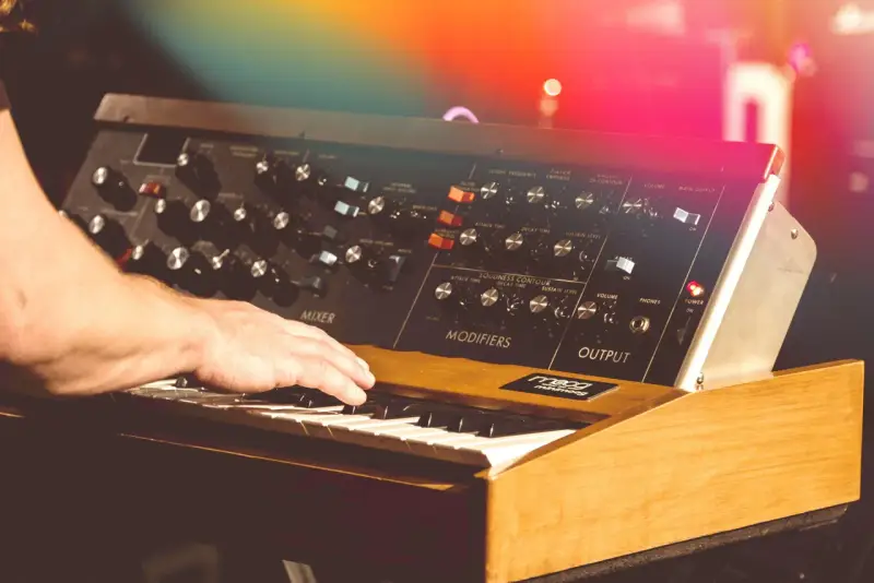 Hand spielt auf einem legendären Minimoog-Synthesizer, der den unverwechselbaren Sound der 70er Jahre prägte.